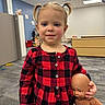 Harper is registered to the contest to win money with this photo: toddler, child, girl, pigtails, red_dress, checkered_pattern, doll, indoor, carpet, office, cabinet, floor, face, person, toy, smile, young_child, blonde_hair, holding, portrait