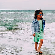 Louisa a rejoint le concours — aidez-le/la à gagner de superbes lots ! child, girl, beach, ocean, waves, sand, water, denim_jacket, dress, sunglasses, barefoot, smiling, curly_hair, summer, outdoor, sea, shore, nature, happy, playful