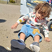 Braydon joined the competition — help win amazing prizes! child, toddler, sitting, outdoor, sand, toy_car, clothing, denim_shorts, sneakers, curly_hair, daylight, shadow, playtime, casual_wear, colorful, expression, vehicle, wheel, young, person