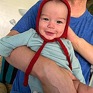 Callan joined the competition — help win amazing prizes! baby, infant, smile, red_bonnet, blue_shirt, adult_arm, child, happy, portrait, indoors, person, cute, holding, face, clothing, skin, hand, headwear, expression, warmth