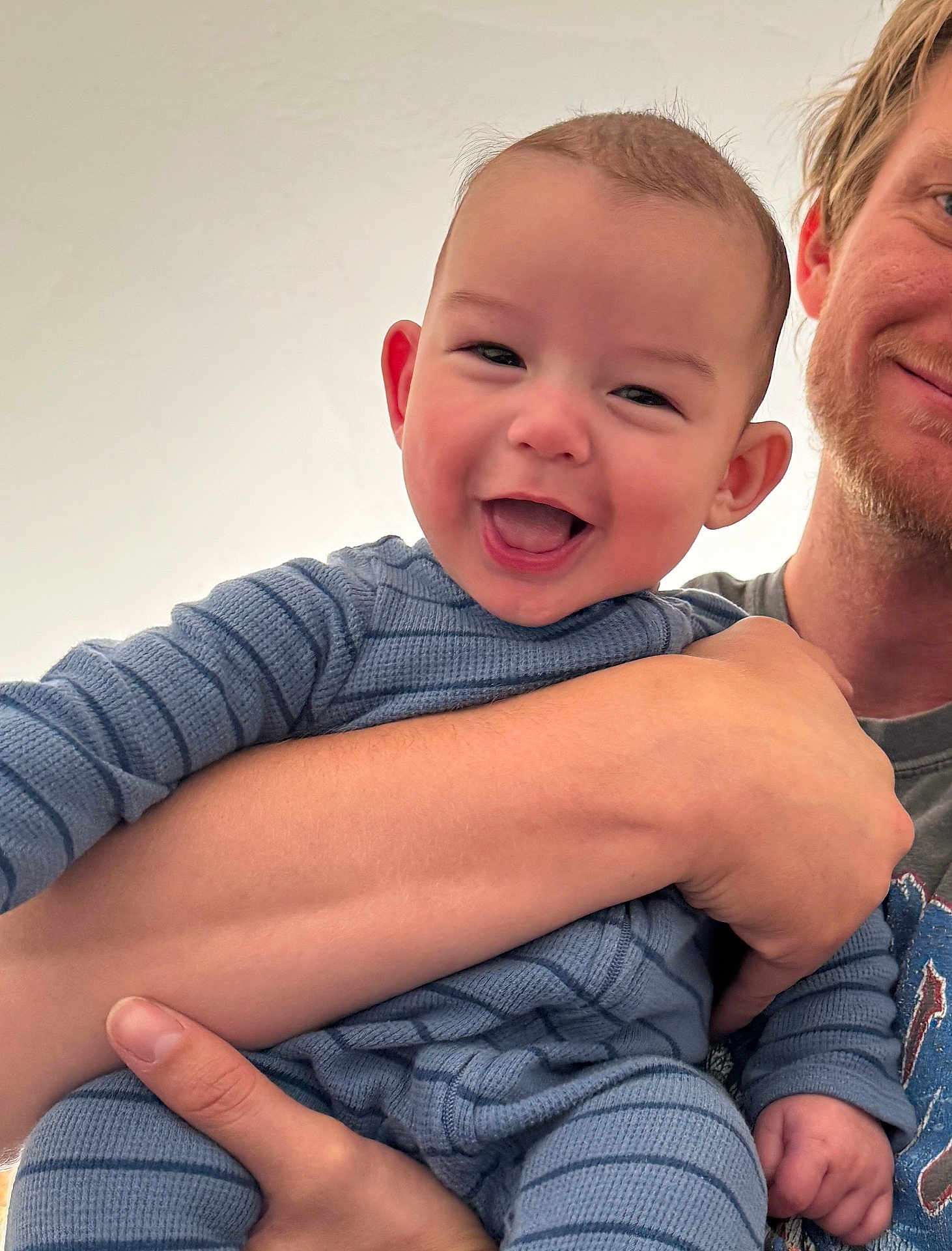 Callan is registered to the contest to win money with this photo: baby, child, smiling, person, adult, holding, blue_clothing, striped, happy, face, arm, hand, portrait, indoor, closeup, skin, head, expression, casual, family