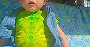 Oliver joined the competition — help win amazing prizes! baby, child, toddler, sitting, blanket, dinosaur_pattern, clothing, green_shirt, blue_pants, sunlight, indoors, portrait, cute, expression, hand, face, head, furniture, casual, cozy