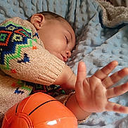 Oliver joined the competition — help win amazing prizes! child, toddler, sleeping, sweater, colorful_clothing, blanket, blue_blanket, toy, basketball_toy, hand, face, cozy, indoor, rest, cute, soft_texture, knitwear, person, portrait, closeup