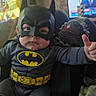 baby, batman_costume, thumbs_up, child, mask, superhero, indoor, couch, blanket, television, person, costume, cute, smile, seat, home, furniture, childhood, fun, portrait