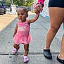 Nayla is registered to the contest to win money with this photo: toddler, child, pink_dress, tutu, crocs, sidewalk, urban, hand_holding, adult, street, mural, daylight, concrete, footwear, person, outdoor, young_child, casual, walking, support