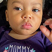 Nayla is registered to the contest to win money with this photo: toddler, child, face, portrait, purple_shirt, text_on_clothing, flowers, hair_buns, expression, eyes, skin, hand, closeup, person, baby, cute, indoor, clothing, pink_lips, young_child