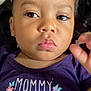toddler, child, face, portrait, purple_shirt, text_on_clothing, flowers, hair_buns, expression, eyes, skin, hand, closeup, person, baby, cute, indoor, clothing, pink_lips, young_child