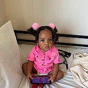 Nayla joined the competition — help win amazing prizes! toddler, child, tablet, bed, pink_clothing, hair_accessories, indoor, curly_hair, serious_expression, cross_legged, technology, blanket, white_sheets, pajamas, furniture, person, room, playing, cute, young_child