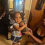 Nayla is registered to the contest to win money with this photo: toddler, child, kitten, cat, indoor, mirror, reflection, person, woman, floor, door, clothing, shorts, sandals, hair, smile, holding, pet, animal, room