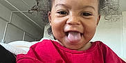 Nayla joined the competition — help win amazing prizes! toddler, child, smiling, red_shirt, curly_hair, tongue_out, indoor, person, happy, playful, cute, portrait, casual_clothing, young_child, face, head, sitting, room, light, expression