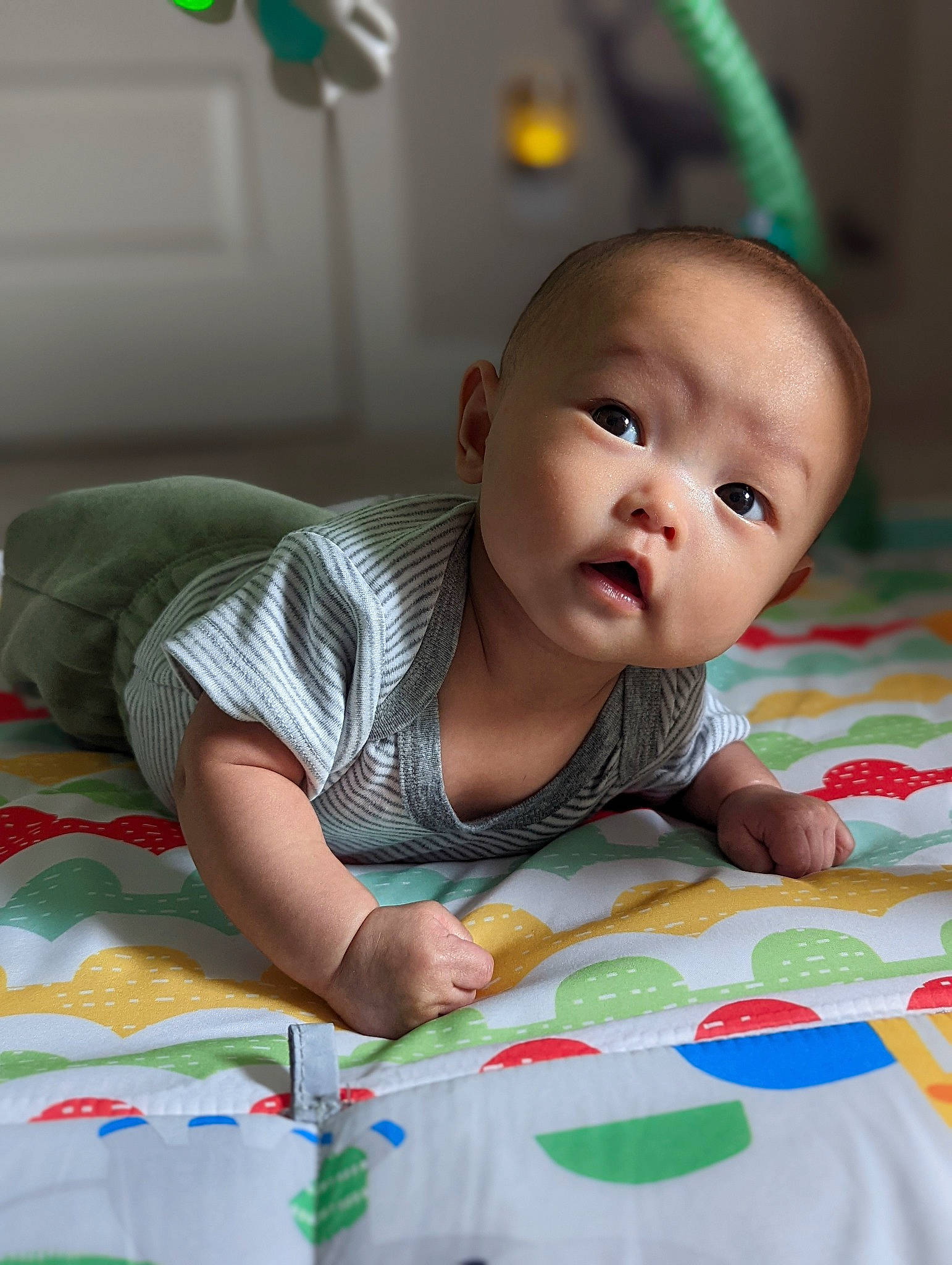 Luke is registered to the contest to win money with this photo: baby, baby_toddler_clothing, cheek, child, eye, face, flooring, fun, happy, iris, linens, nose, pattern, person, product, room, sitting, skin, toddler, tummy_time