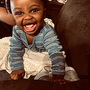 Hunter is registered to the contest to win money with this photo: baby, smiling, crawling, onesie, striped_clothing, indoor, couch, blanket, bottle, happy, child, infant, person, home, furniture, cute, face, expression, playful, young