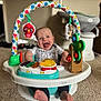 baby, smile, toy, activity_center, carpet, indoor, happy, child, infant, face, feet, clothing, colorful, plastic, furniture, living_room, play, seat, person, cute