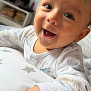 Thiago joined the competition — help win amazing prizes! baby, bedroom, child, closeup, cushion, cute, expression, face, hand, happy, indoor, infant, pajamas, person, portrait, resting, smiling, soft_lighting, star_pattern, young_child