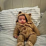 baby, infant, knitted_clothing, hood, bear_ears, buttoned_sweater, cozy, bed, pillow, blanket, cute, warm, footwear, soft_toys, child, portrait, indoors, comfortable, expression, small_hands