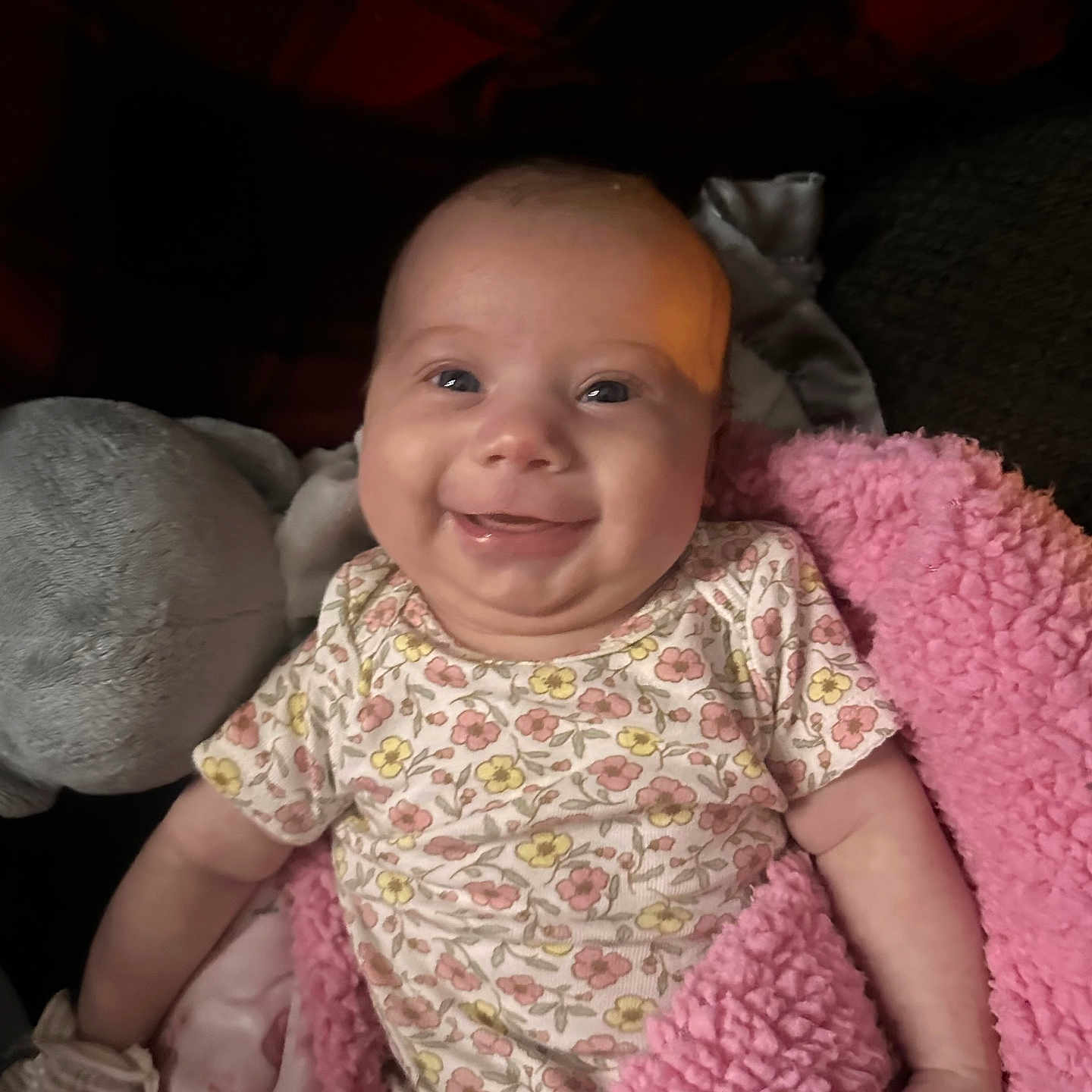Ruby is registered to the contest to win money with this photo: baby, blanket, child, comfort, cozy, cute, face, floral_onesie, hand, happy, indoors, infant, person, pink, plush_toy, portrait, skin, smiling, soft, young