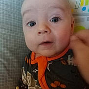 Lincoln joined the competition — help win amazing prizes! baby, close_up, face, infant, pacifier, colorful_clothing, patterned_background, curious_expression, wide_eyes, indoor, child, playmat, cushion, orange_trim, young_child, portrait, cute, hand, soft_lighting, baby_girl_or_boy