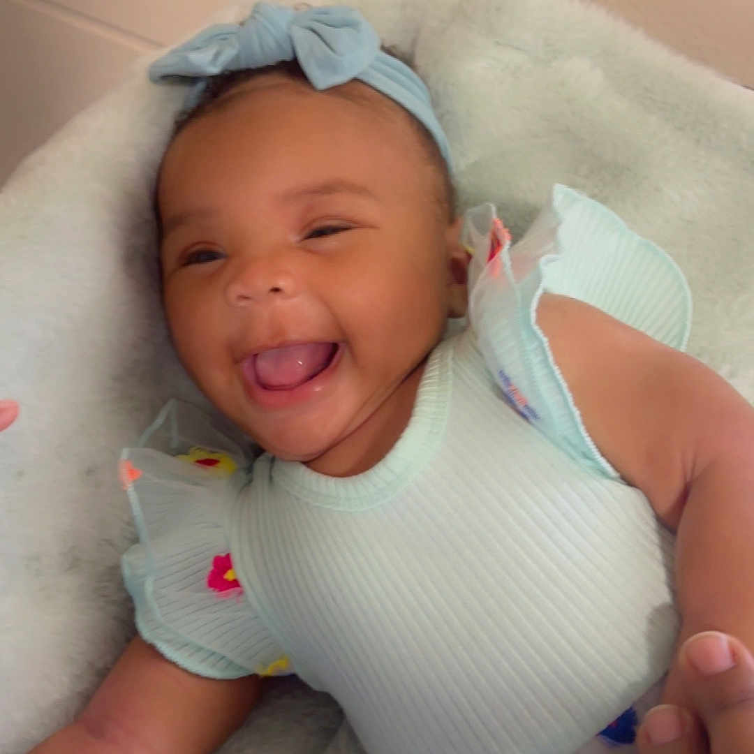 Psalms-Marie is registered to the contest to win money with this photo: baby, child, closeup, cushion, cute, dress, hand, happy, headband, holding, indoors, infant, joy, laughing, person, portrait, skin, smiling, soft, toddler