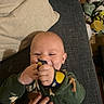 Tazz is registered to the contest to win money with this photo: adult_hand, baby, blanket, candid_photo, casual, child, colorful_toy, couch, face, green_clothing, hands, happy, home, indoor, infant, lying_down, portrait, sitting, smiling, toy