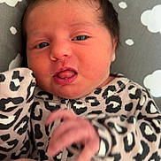 Hazel joined the competition — help win amazing prizes! newborn, baby, infant, hand, onesie, leopard_print, face, expression, cushion, cloud_pattern, skin, person, closeup, indoor, child, cute, tiny_hand, support, soft, resting