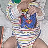 newborn, baby, sleeping, pacifier, superman, superhero, striped_clothing, onesie, infant, portrait, indoors, lying_down, blanket, towel, dark_hair, closed_eyes, hands, legs, colorful, peaceful