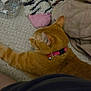 cat, orange_tabby, collar, fabrics, patterned, textured_surface, home_interior, relaxing, pet, domestic_cat, soft, pink, brown, black, white, striped, stuffed_toy, blanket, cozy, casual