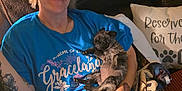 Daisyloo is registered to the contest to win money with this photo: woman, smiling, puppy, dog, couch, blanket, pillow, tattoo, blue_tshirt, indoor, relaxing, cute, sleeping_dog, home, comfort, hand, face, person, leisure, pet