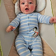 Elijah is registered to the contest to win money with this photo: baby, infant, onesie, blue_stripes, penguin_patch, cushion, lounger, child, cute, portrait, smiling, indoor, soft_toys, sleeping_bed, apparel, expression, person, small_child, warm, comfortable