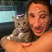 Silvy is registered to the contest to win money with this photo: arm, candid, car_interior, cat, closeup, collar, domestic_animal, expression, eyes, face, fur, gray_tabby, happy, hugging, night, person, pet, smiling, whiskers, window