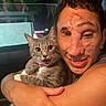 arm, candid, car_interior, cat, closeup, collar, domestic_animal, expression, eyes, face, fur, gray_tabby, happy, hugging, night, person, pet, smiling, whiskers, window
