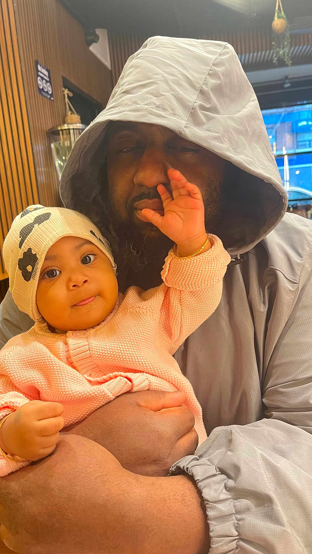 Marie joined the competition — help win amazing prizes! baby, adult, child, hoodie, hat, indoor, person, holding, cute, playful, face, hand, sweater, skin, closeup, warm_lighting, expression, interaction, love, family