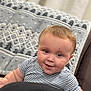 baby, child, striped_shirt, face, eyes, smile, curtain, blanket, pattern, indoor, cute, infant, plush, person, head, cheeks, soft, cozy, furniture, curious
