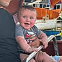baby, child, adult, smile, happy, outdoor, ride, amusement_park, metal_bar, clothing, shorts, tshirt, person, holding, blue_eyes, rosy_cheeks, legs, hand, seat, casual