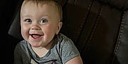 Rowan is registered to the contest to win money with this photo: baby, child, smiling, happy, blue_eyes, short_hair, grey_shirt, graphic_tshirt, sitting, leather_chair, indoor, cute, portrait, infant, young_child, human, skin, one_person, casual_clothing, comfort