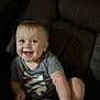 baby, child, smiling, happy, blue_eyes, short_hair, grey_shirt, graphic_tshirt, sitting, leather_chair, indoor, cute, portrait, infant, young_child, human, skin, one_person, casual_clothing, comfort