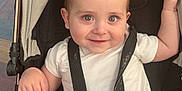 Eli is registered to the contest to win money with this photo: baby, stroller, child, infant, harness, white_clothing, smiling, seat, person, cute, sitting, straps, indoor, happy, young_child, head, face, skin, hand, legs