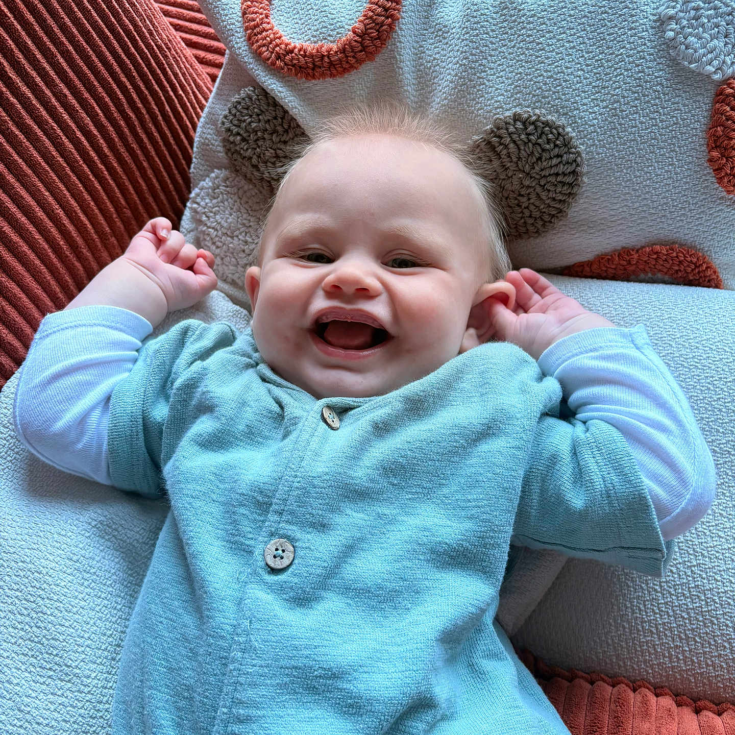 Louis a rejoint le concours — aidez-le/la à gagner de superbes lots ! baby, blue_outfit, buttoned_shirt, cheerful, clothing, couch, cute, face, happy, home, indoor, infant, light, person, pillow, raised_arms, relaxing, smiling, soft_fabric, texture
