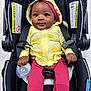 baby, baby_bottle, black_car_seat, car_seat, child, clothing, cute, floor, footwear, happy, indoors, infant, pink_pants, portrait, safety, seated, smiling, socks, straps, yellow_hoodie