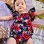 baby, infant, child, floral_clothing, headband, blanket, horse_illustration, purple_background, red_flowers, lying_down, arms_outstretched, cute, adorable, portrait, smiling, soft_texture, indoor, colorful, young_child, person