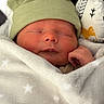 Lucas is registered to the contest to win money with this photo: newborn, baby, sleeping, hat, green_hat, blanket, white_blanket, stars, pillow, patterned_pillow, cozy, soft, infant, closeup, face, peaceful, cute, wrapped, resting, indoor