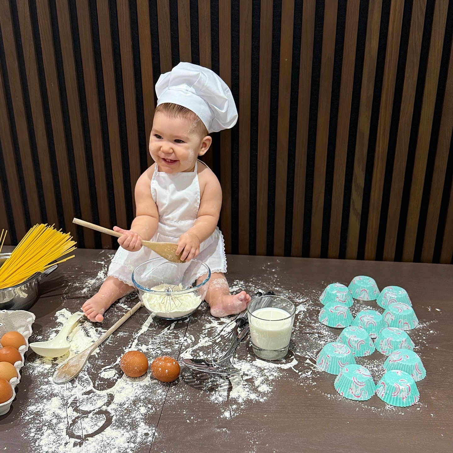 Rea Michelle is registered to the contest to win money with this photo: apron, baby, baking, chef_hat, child, cooking, cute, eggs, flour, glass_bowl, indoors, kitchen, messy, milk, playful, sitting, smiling, table, whisk, wooden_spoon