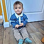 Jake a rejoint le concours — aidez-le/la à gagner de superbes lots ! toddler, child, baby, floor, wooden_floor, sitting, blue_sweatshirt, beige_pants, socks, indoor, door, curious, expression, young_child, person, portrait, casual_clothing, home, smile, small_hands