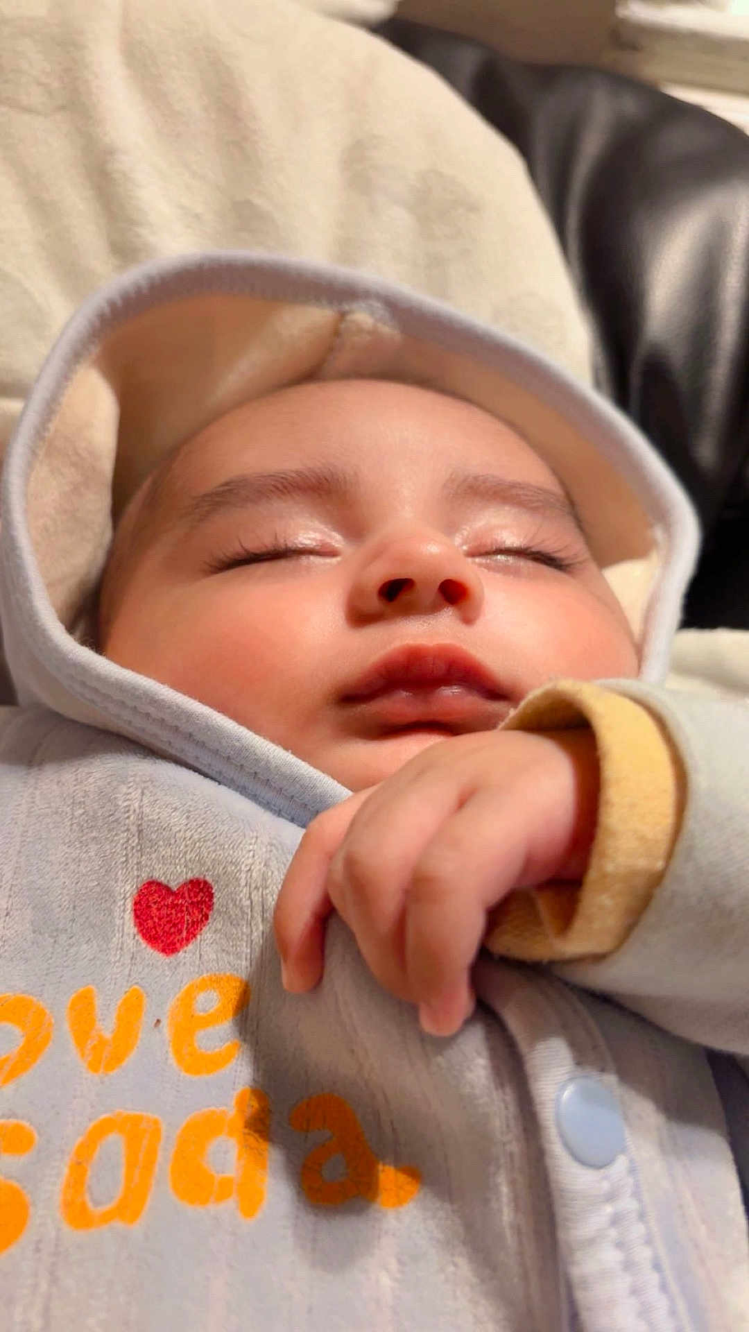 Musa is registered to the contest to win money with this photo: baby, sleeping, hood, hand, face, cozy, infant, soft_lighting, closeup, peaceful, cute, child, clothing, nap, indoor, portrait, warm, adorable, resting, love