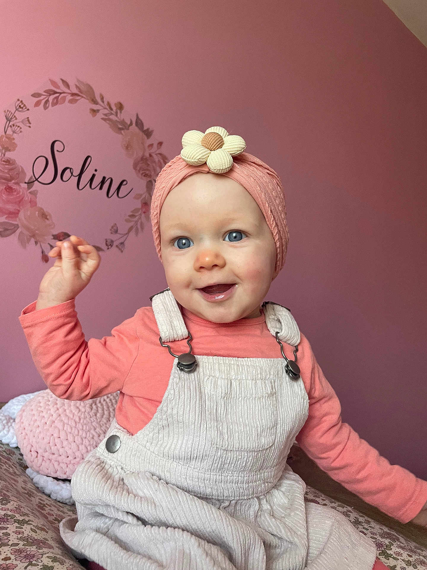 Soline a rejoint le concours — aidez-le/la à gagner de superbes lots ! baby, infant, child, headband, flower_headband, pink_wall, nursery, overalls, pink_clothing, smile, blue_eyes, portrait, indoor, bedroom, knitted_pillow, decorative_decal, raised_hand, cheeks, candid, soft_lighting