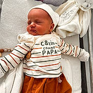 Eden a rejoint le concours — aidez-le/la à gagner de superbes lots ! newborn, baby, sleeping, striped_shirt, orange_pants, plush_toy, blanket, crib, cozy, cute, infant, child, resting, soft_toy, white, toddler, peaceful, indoors, warm_clothing, face