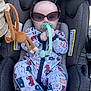 baby, infant, sunglasses, pacifier, car_seat, toy_monkey, blanket, onesie, animal_pattern, clip, headrest, safety_label, plush_toy, cute, sitting, outdoor_light, infant_clothing, stroller, hand, portrait