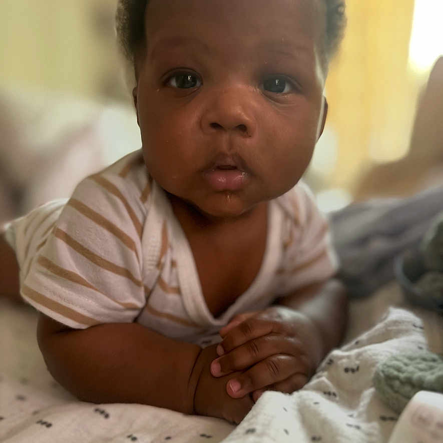 Dierre is registered to the contest to win money with this photo: baby, blanket, candid, child, closeup, curly_hair, cute, expression, face, hands, indoor, infant, lying_down, newborn, person, portrait, skin, soft_light, striped_clothing, toddler