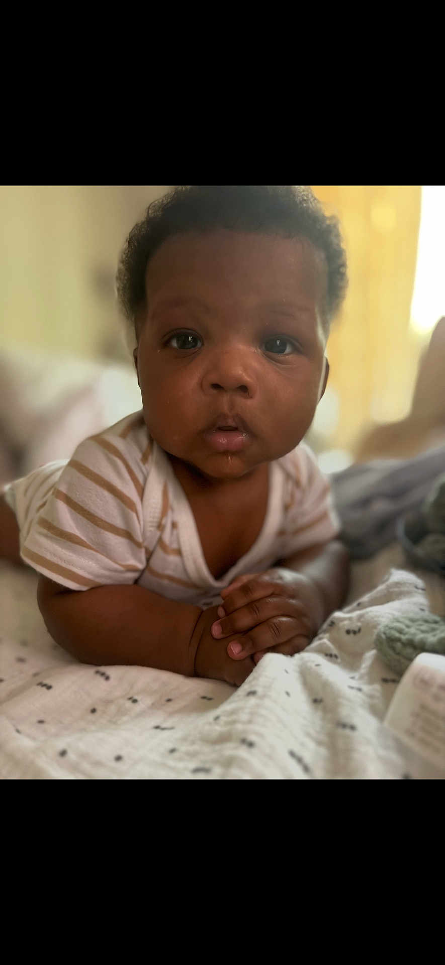 Dierre is registered to the contest to win money with this photo: baby, infant, child, face, hands, blanket, striped_clothing, curly_hair, indoor, soft_light, cute, lying_down, closeup, portrait, skin, expression, newborn, person, toddler, candid