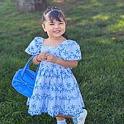 Arabella is registered to the contest to win money with this photo: child, girl, smile, blue_dress, backpack, grass, outdoor, happy, young_child, shoes, hair_clips, sunlight, greenery, fashion, portrait, cute, standing, playful, daylight, casual