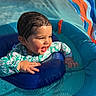 toddler, child, pool, water, swimwear, wet_hair, inflatable_pool, sunlight, happy, smiling, colorful, blue, orange, green, play, summer, outdoor, baby, splash, fun